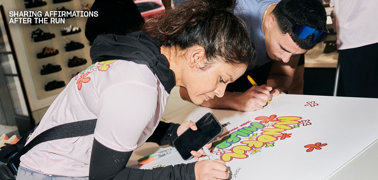 Image of two people writing affirmations on a board after a run, with shoe shelves behind.