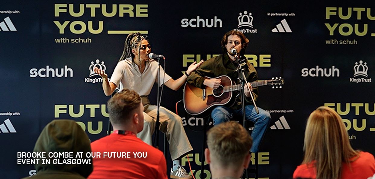 Image of Brooke Combe performing at a “Future You” event with audience and charity logos in view.